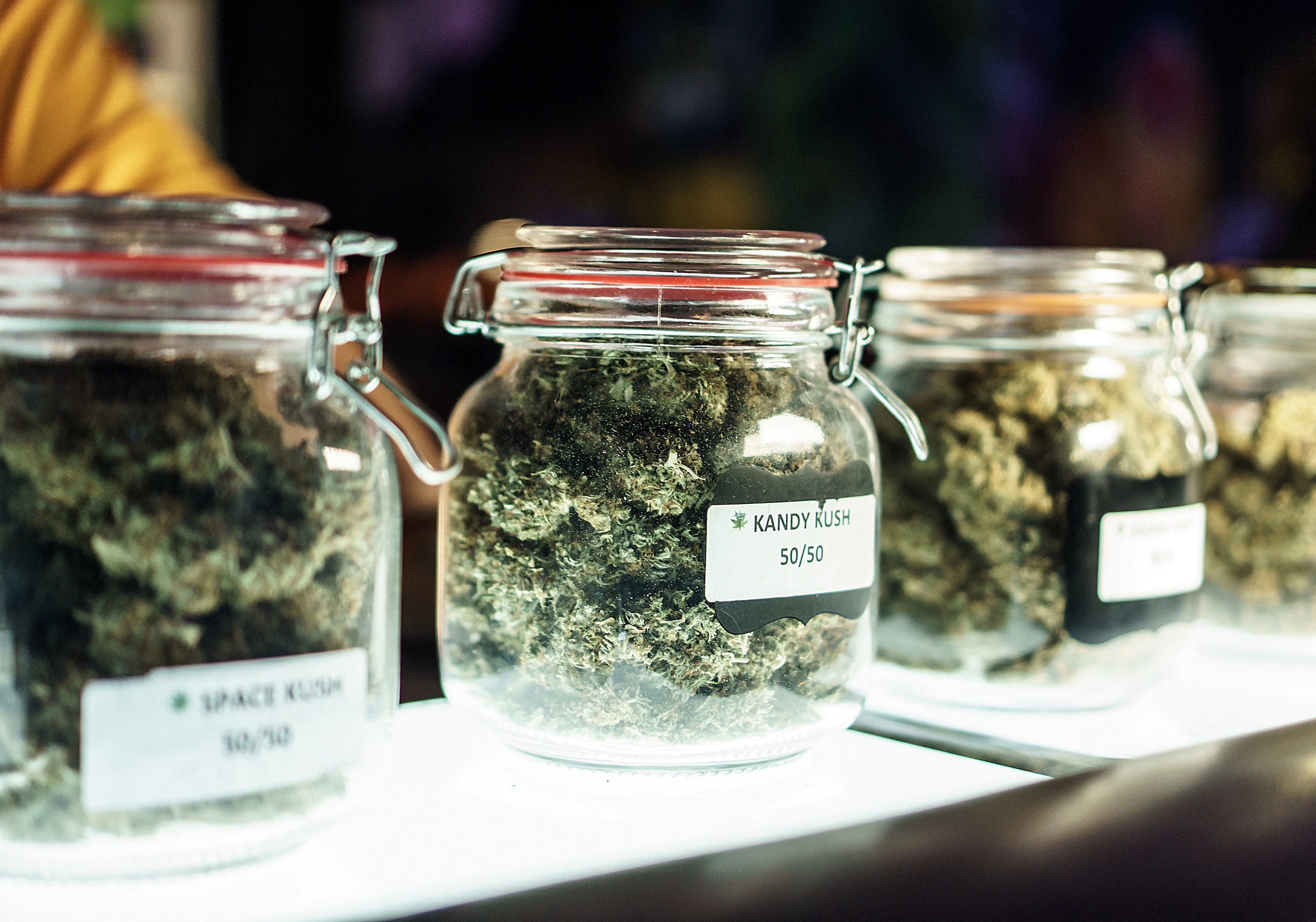 Jars of different cannabis strains labeled with names and ratios.