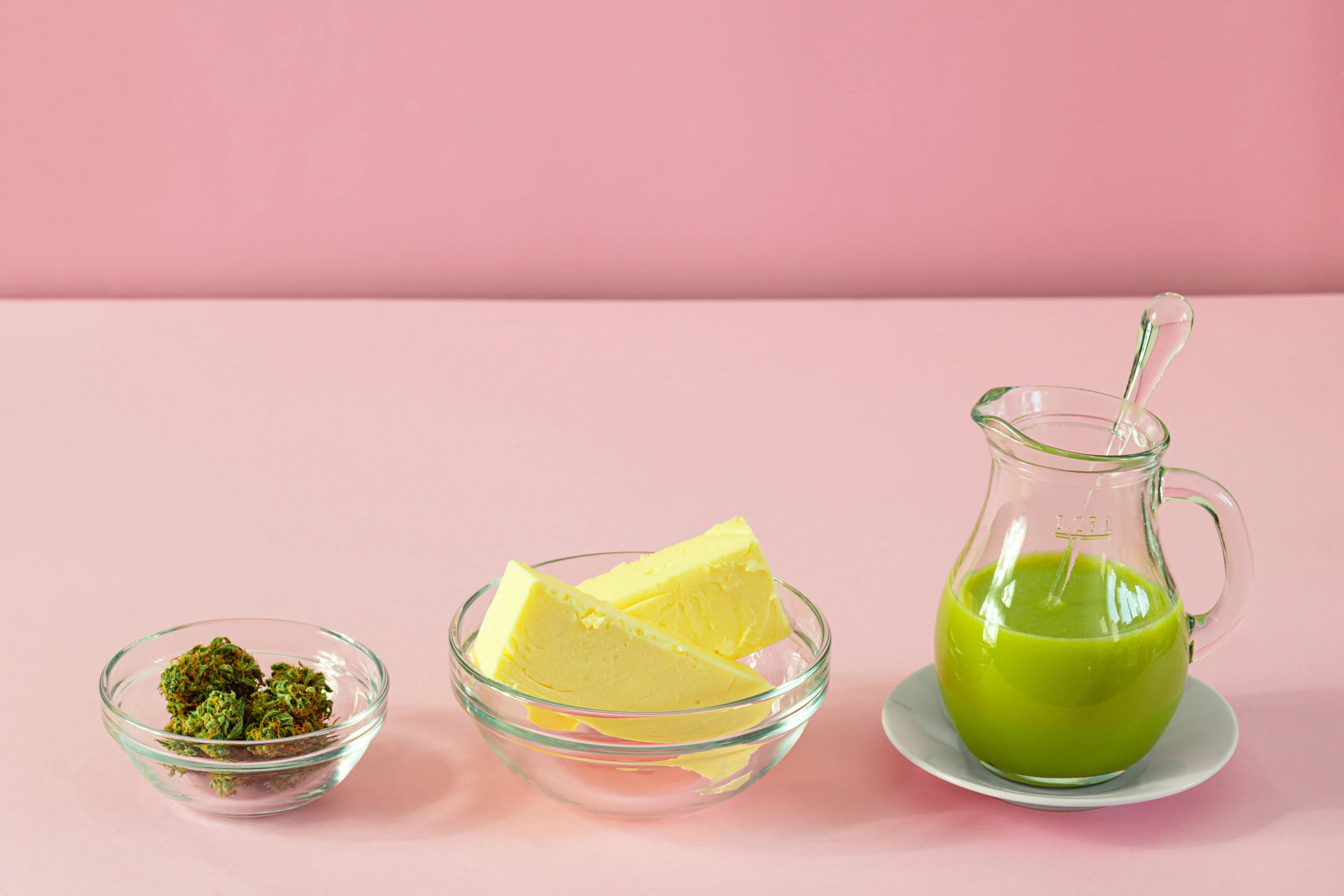 Cannabis, butter, and cannabutter on a pink background.