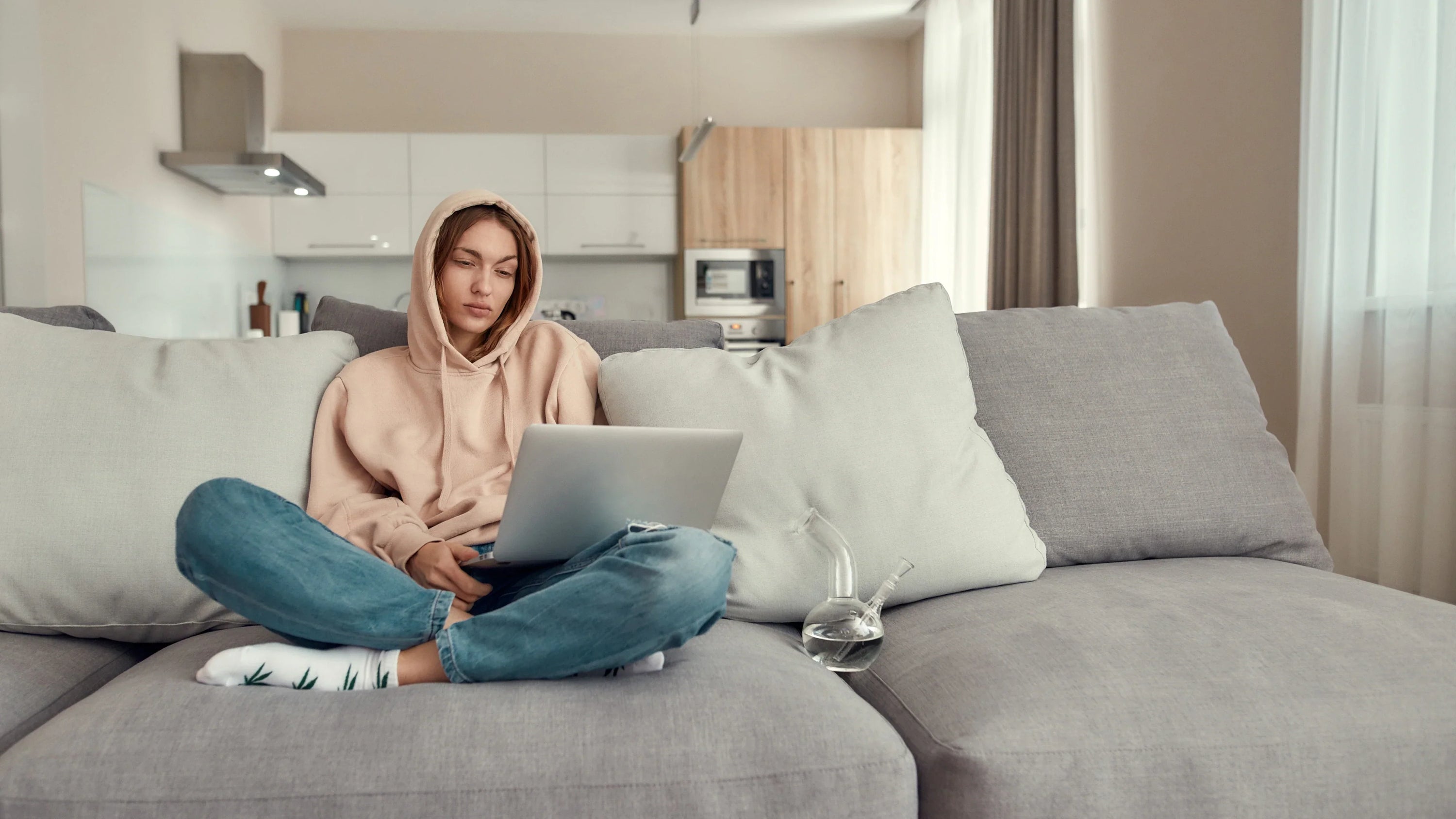 Young woman sitting on the couch next to her bong. 