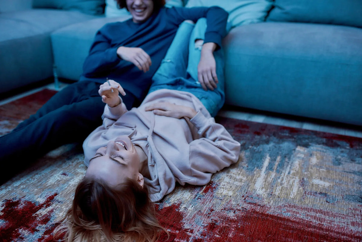 Stoned young couple relax on the floor beside the couch.